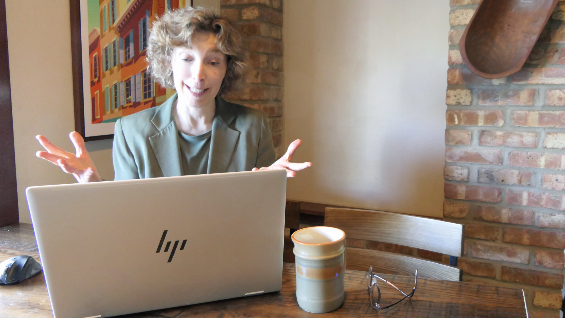 Kim talking to an unseen client on her laptop in a virtual coaching session with her hands active in the conversation.