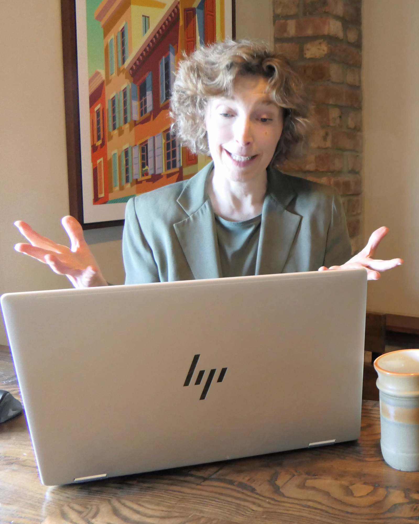 Kim talking to an unseen client on her laptop in a virtual coaching session with her hands active in the conversation.